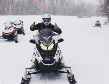 a person on a snowmobile gives two thumbs up