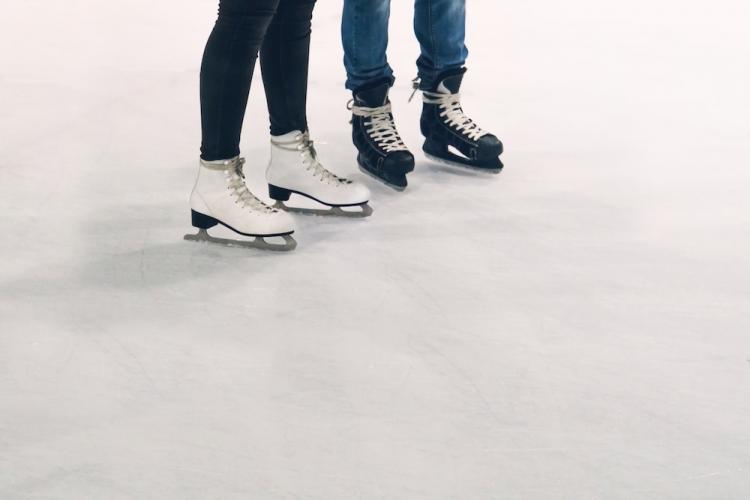 two pairs of feet in ice skates on an ice rink