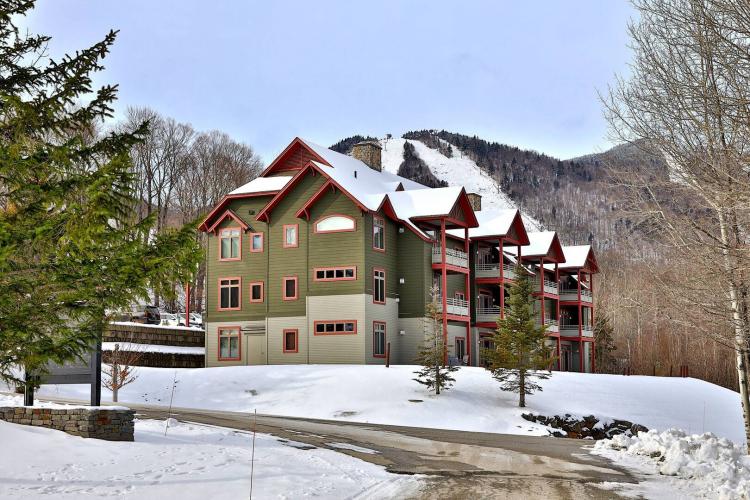 The Lodges at Sunrise - a large brown ski lodge in Killington - sits snow-covered in the wintertime