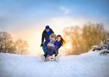 family sledding with child on a snowy hill