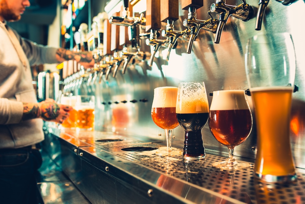 different beers lined up under the taps on a bar
