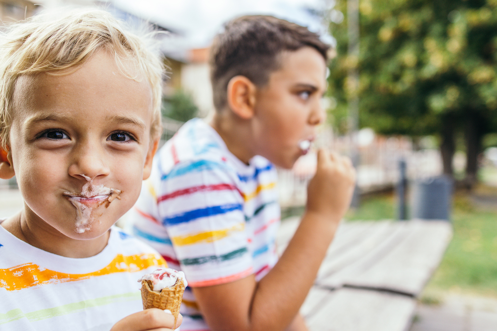 cute little boy eating ice cream with it smeared on his face