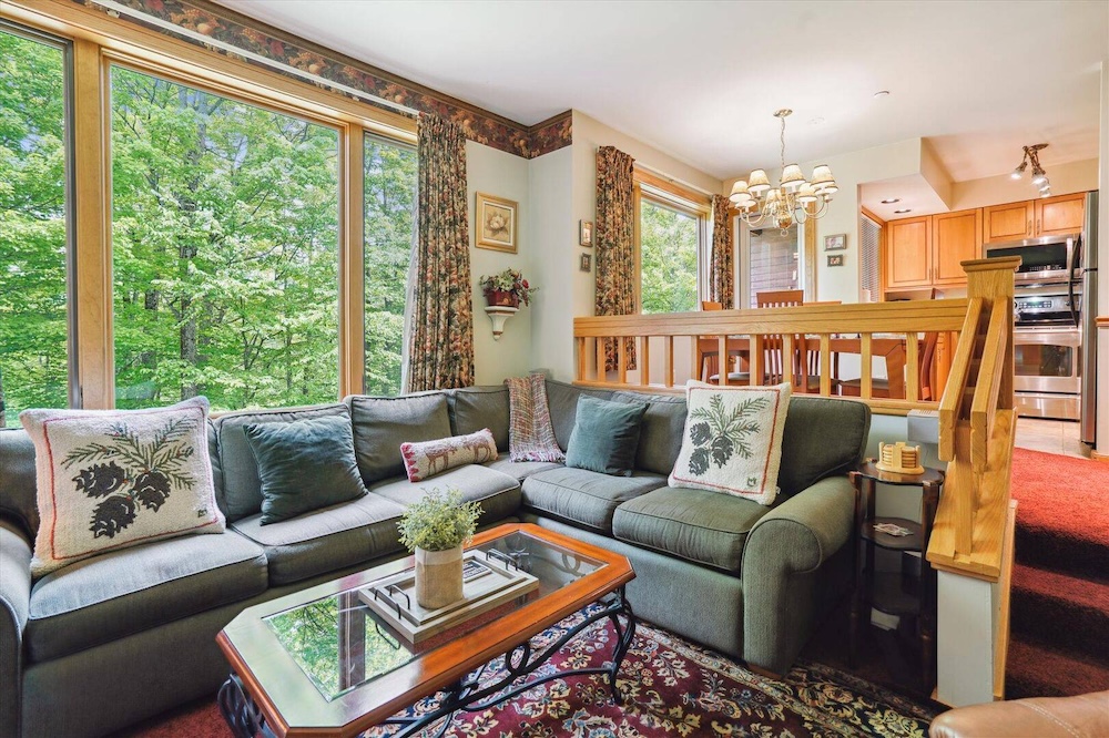 Living room view of a killington, vt condo with trees outside the window