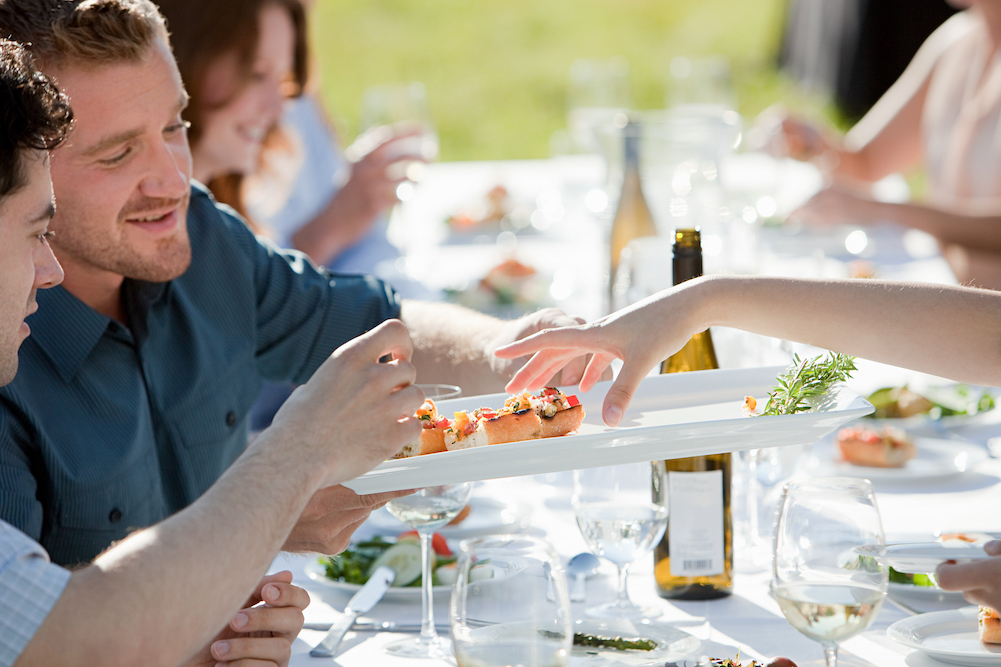 people trying small appetizers at a nice outdoor dinner