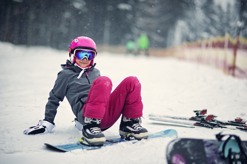 young person on a snowboard getting ready to stand up